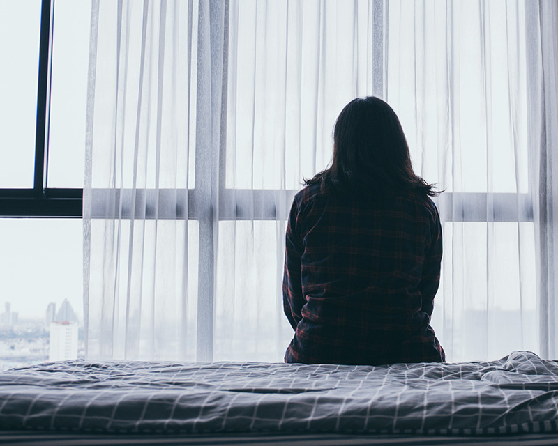 Woman sitting on a bed experiencing borderline personality disorder