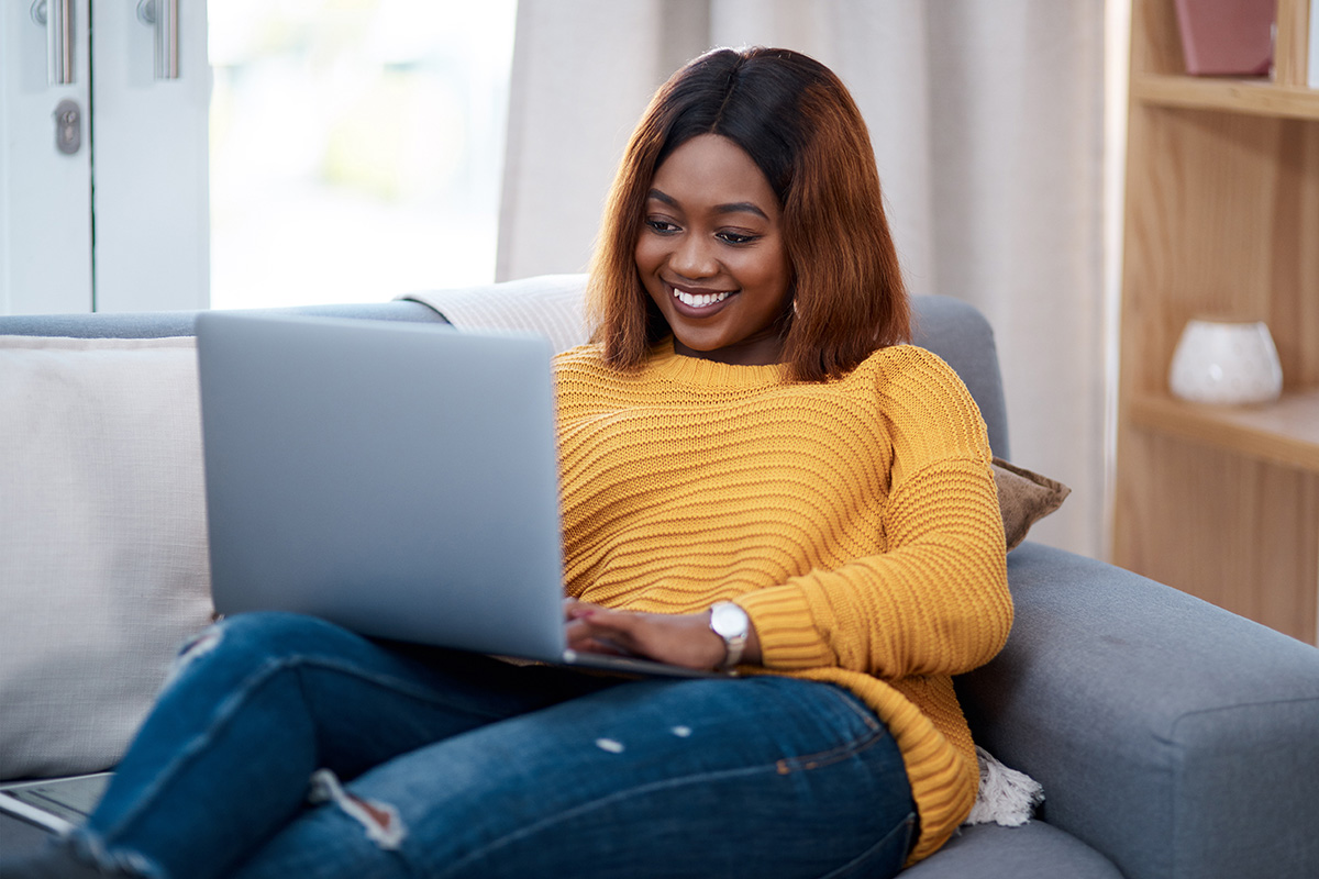 Black woman on the couch with a laptop finding a therapist online