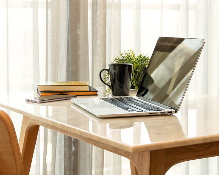 Laptop on a desk with coffee cup, ready for virtual therapy